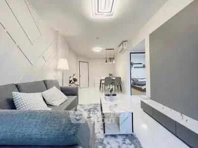 Modern living room with stylish decor and open layout leading to dining area and bedroom.