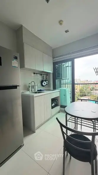 Modern kitchen with sleek cabinetry and city view from window, featuring compact dining area.
