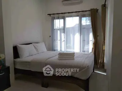 Cozy bedroom with natural light and neatly arranged bed in modern home.