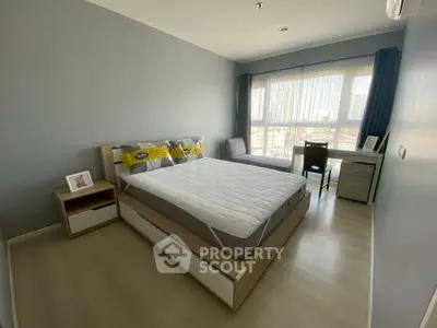 Modern bedroom with large window and city view, featuring a stylish bed and desk area.