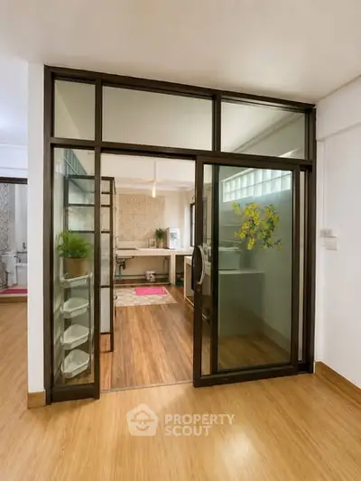 Modern study room with glass partition and wooden flooring in a stylish apartment.