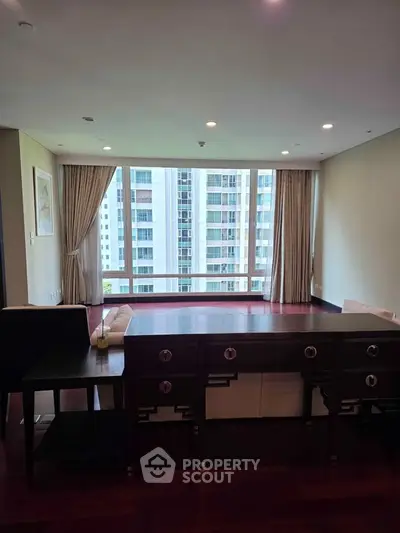 Spacious living room with large windows offering stunning city views in a modern apartment.
