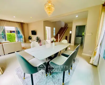 Luxurious open-plan living and dining area with elegant chandelier and modern decor.
