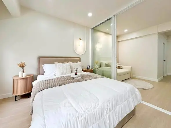 Modern bedroom with cozy decor and adjoining living area in a stylish apartment.