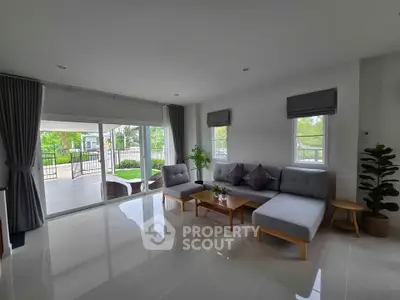 Spacious living room with modern furniture and large windows overlooking a lush garden.