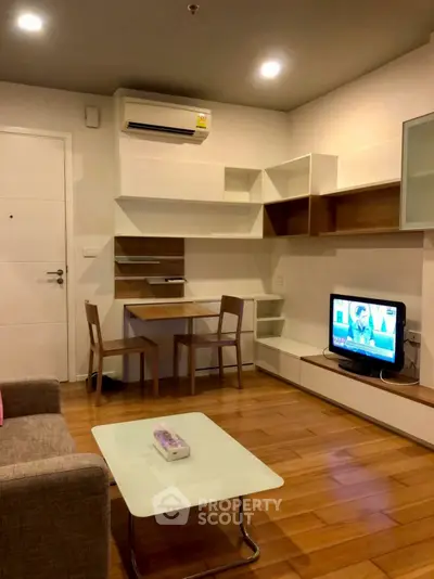 Modern living room with wooden flooring, TV, and stylish furniture