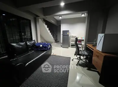 Modern home office with sleek black leather sofa and ergonomic chair, perfect for productivity.