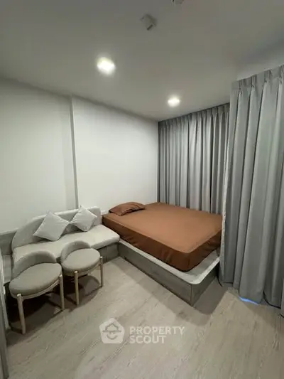 Modern bedroom with cozy bed and stylish seating area, featuring elegant curtains and soft lighting.
