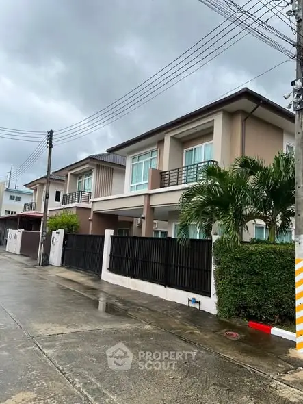Modern two-story house with sleek design and lush greenery on a rainy day.