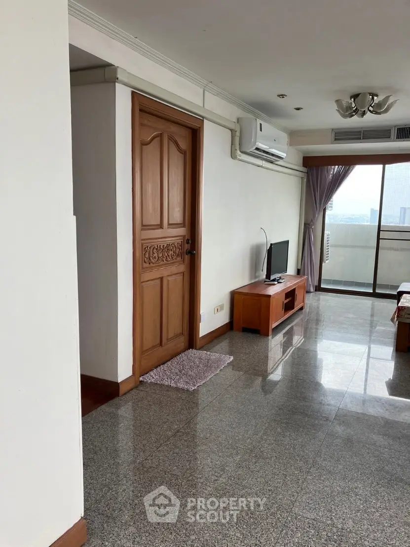 Spacious living room with balcony and city view, featuring modern decor and natural light.