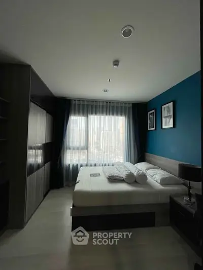 Modern bedroom with city view, featuring elegant decor and natural light through large window.