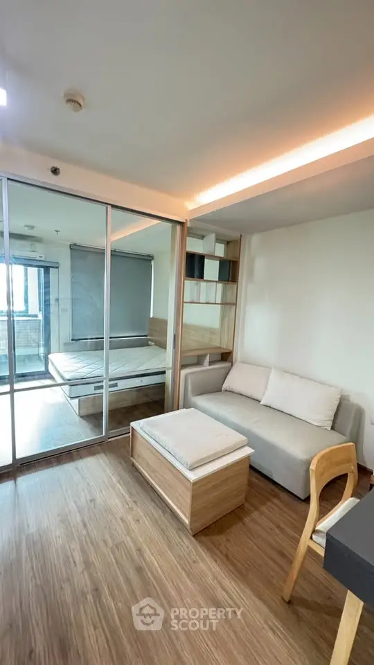 Modern living room with wooden flooring and sliding glass doors leading to bedroom