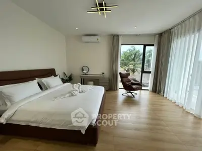 Spacious bedroom with modern decor and large windows offering natural light and scenic views.