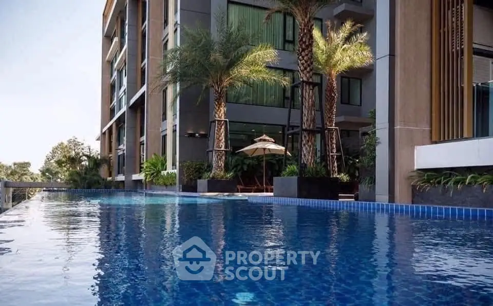 Luxurious modern apartment building with stunning poolside view and lush palm trees.
