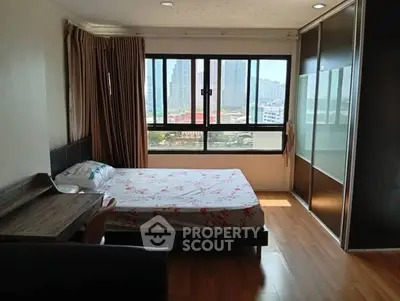 Spacious bedroom with large window offering city view and ample natural light.