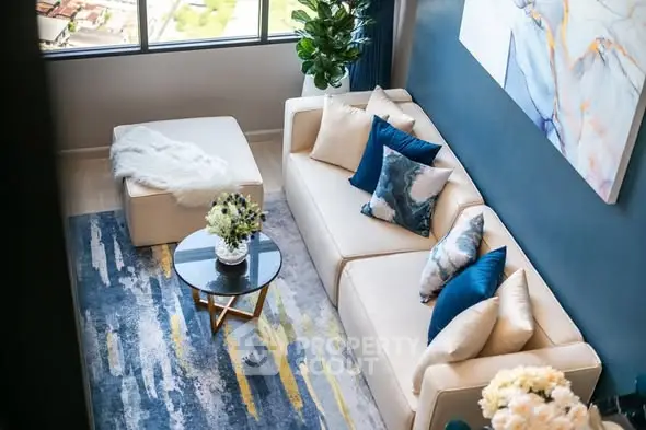 Stylish modern living room with plush sofa, abstract art, and large window view.