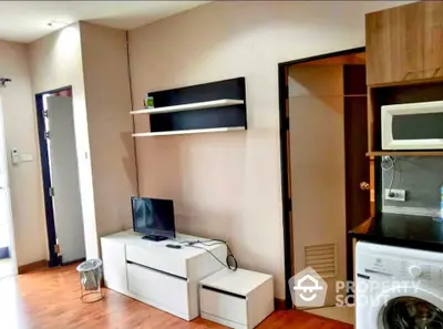 Modern apartment living room with TV, shelves, and kitchen appliances