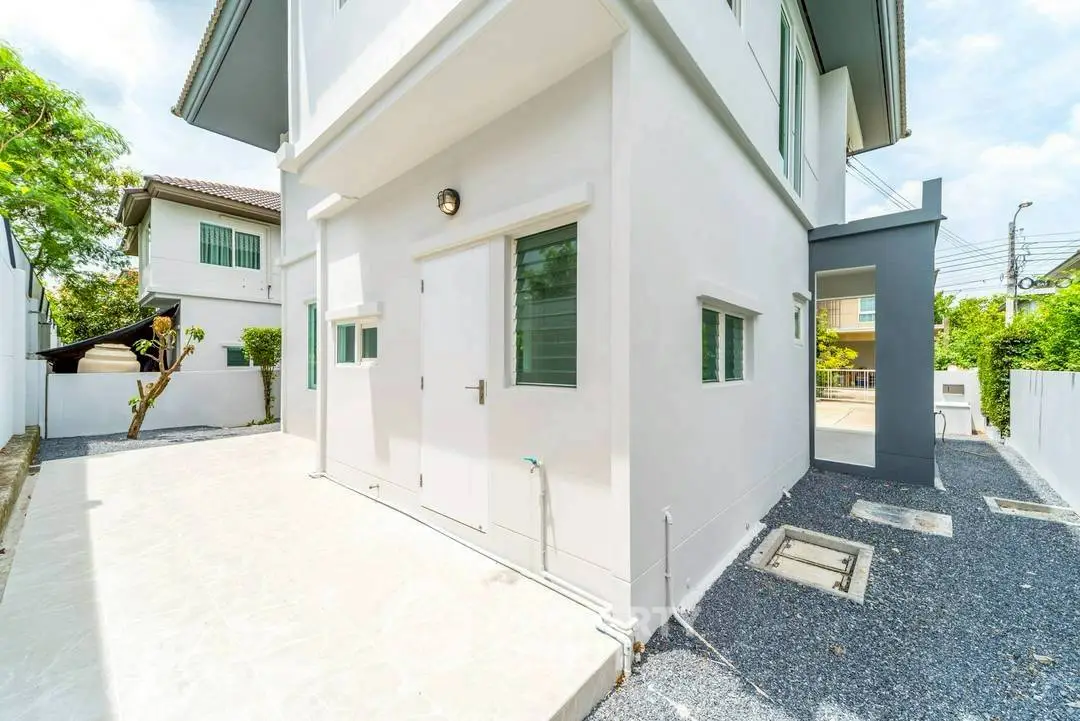 Modern white exterior of a two-story house with clean lines and spacious outdoor area.