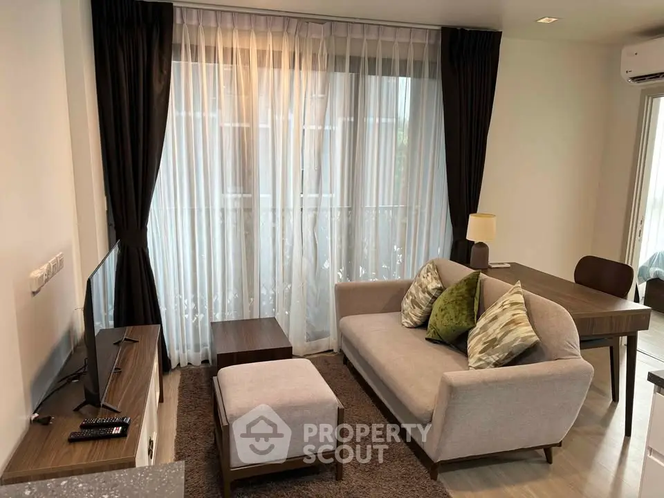 Modern living room with cozy sofa, stylish decor, and natural light from large windows.