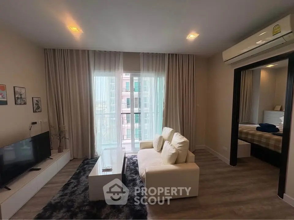 Modern living room with cozy sofa, TV, and balcony view in stylish apartment.