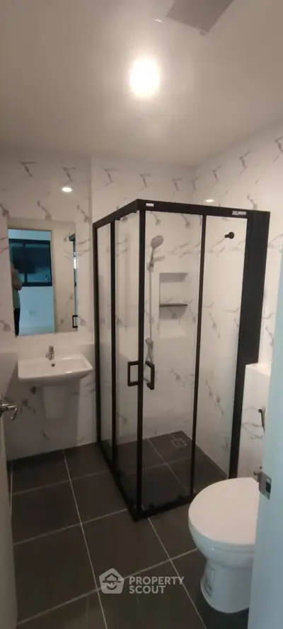 Modern bathroom with glass shower enclosure and sleek fixtures in a contemporary apartment.