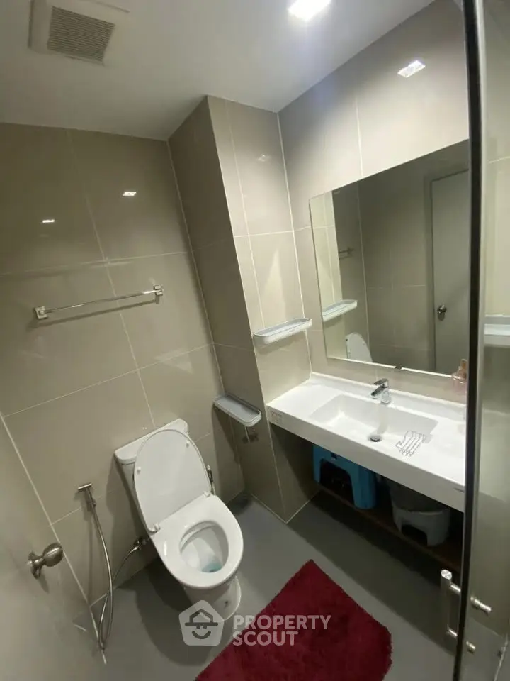 Modern bathroom with sleek fixtures and large mirror in contemporary apartment.