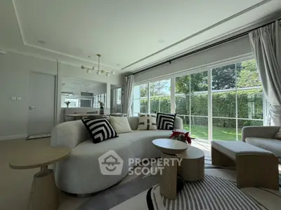 Luxurious living room with modern furniture and large windows overlooking a garden