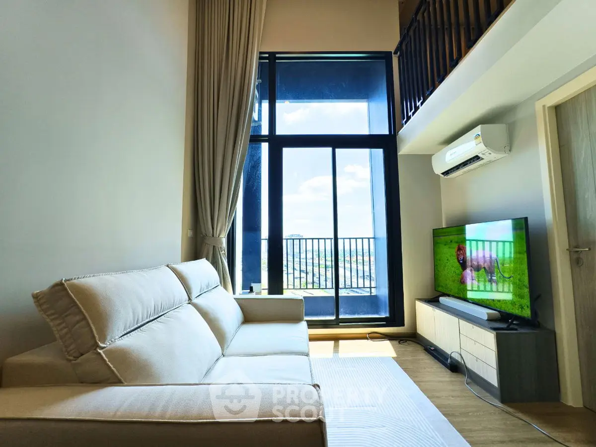 Modern living room with high ceiling and balcony view, featuring a cozy sofa and wall-mounted TV.