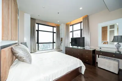 Luxurious bedroom with city view, elegant furnishings, and ample natural light.