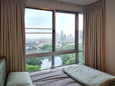 Spacious bedroom with panoramic city view and large windows in modern apartment.