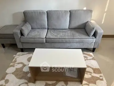 Modern living room with gray sofa and white coffee table on patterned rug.