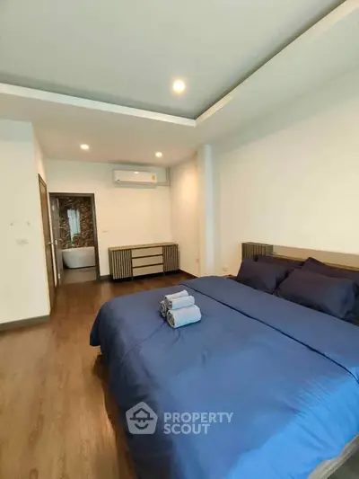 Modern bedroom with blue bedding and wooden flooring in a stylish apartment.