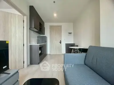 Modern living room with sleek furniture and open kitchen layout in a stylish apartment.