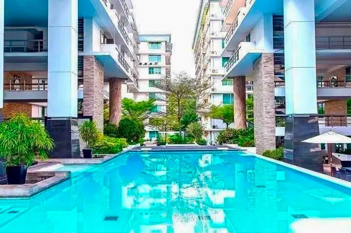 Luxurious modern apartment complex with stunning pool and lush greenery.