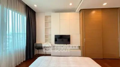 Modern bedroom with built-in storage and large window offering city views.