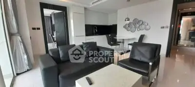 Modern living room with sleek black furniture and open kitchen layout