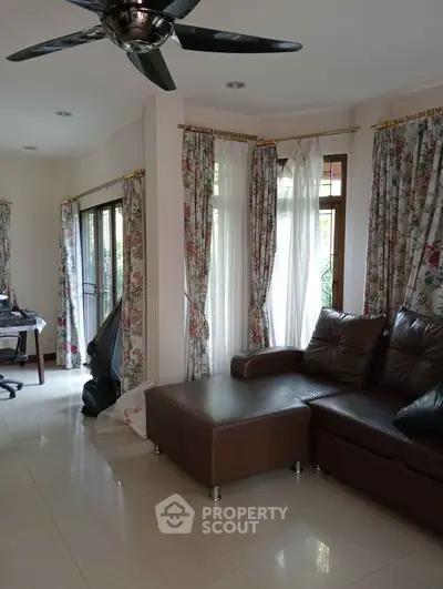 Spacious living room with elegant curtains and modern brown leather sofa