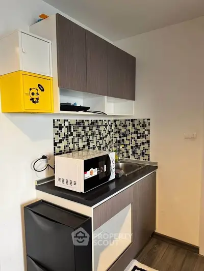 Modern compact kitchen with stylish backsplash and microwave, perfect for urban living.