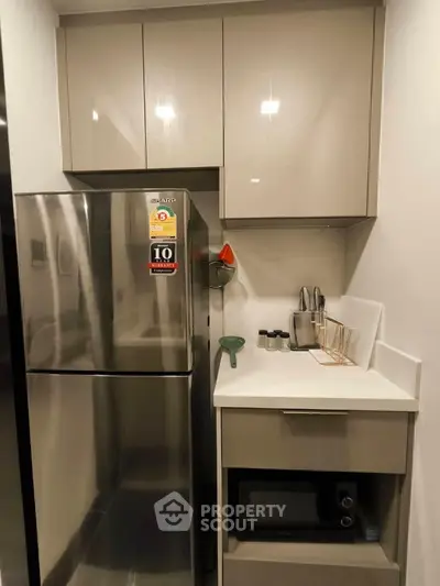 Modern compact kitchen with stainless steel fridge and microwave