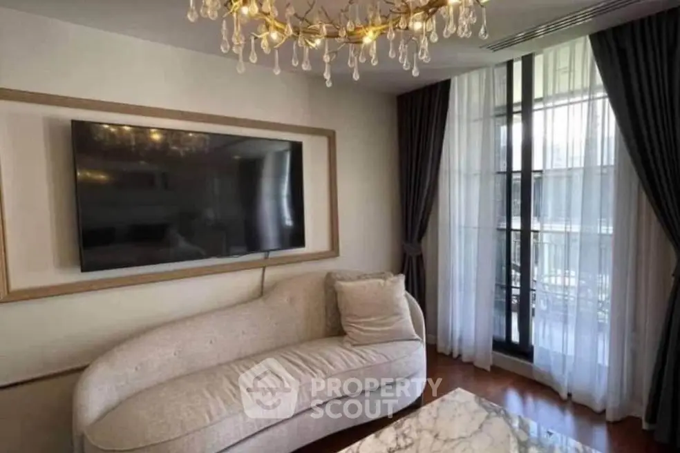Elegant living room with modern chandelier and large TV, featuring a stylish sofa and floor-to-ceiling windows.