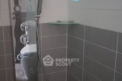 Modern bathroom shower with sleek fixtures and glass shelf in stylish tiled setting.