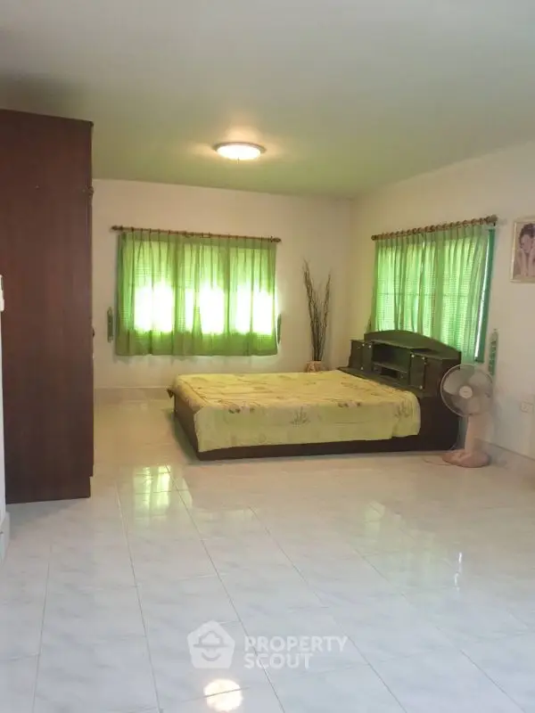 Spacious bedroom with green curtains and modern furnishings.