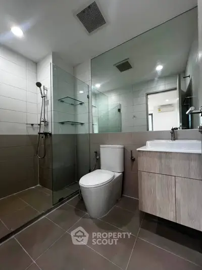 Modern bathroom with glass shower and sleek fixtures in contemporary apartment.