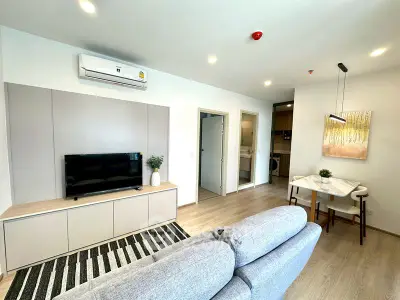 Modern living room with cozy sofa, TV, and dining area in open layout apartment.