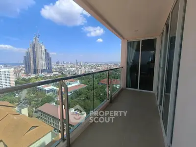 Spacious balcony with stunning cityscape view and modern glass railing.