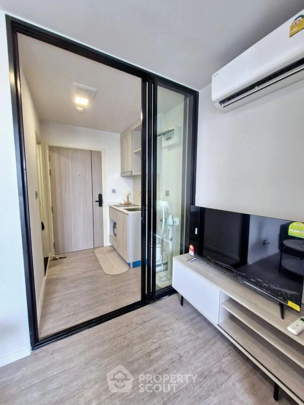 Modern apartment interior with sleek kitchen and cozy living area featuring air conditioning and TV setup.