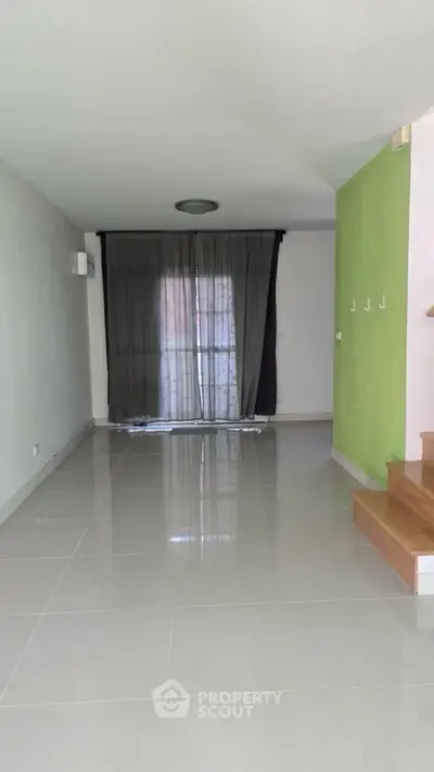 Spacious empty living room with tiled floor and large window, ideal for customization.