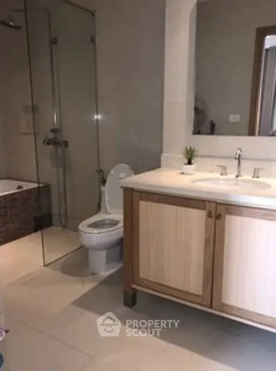 Modern bathroom with glass shower and wooden vanity in a stylish home.