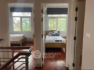 Bright and airy bedroom with wooden flooring and large windows overlooking greenery.