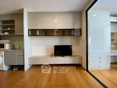 Modern living room with wooden flooring, built-in cabinets, and a compact kitchen area.